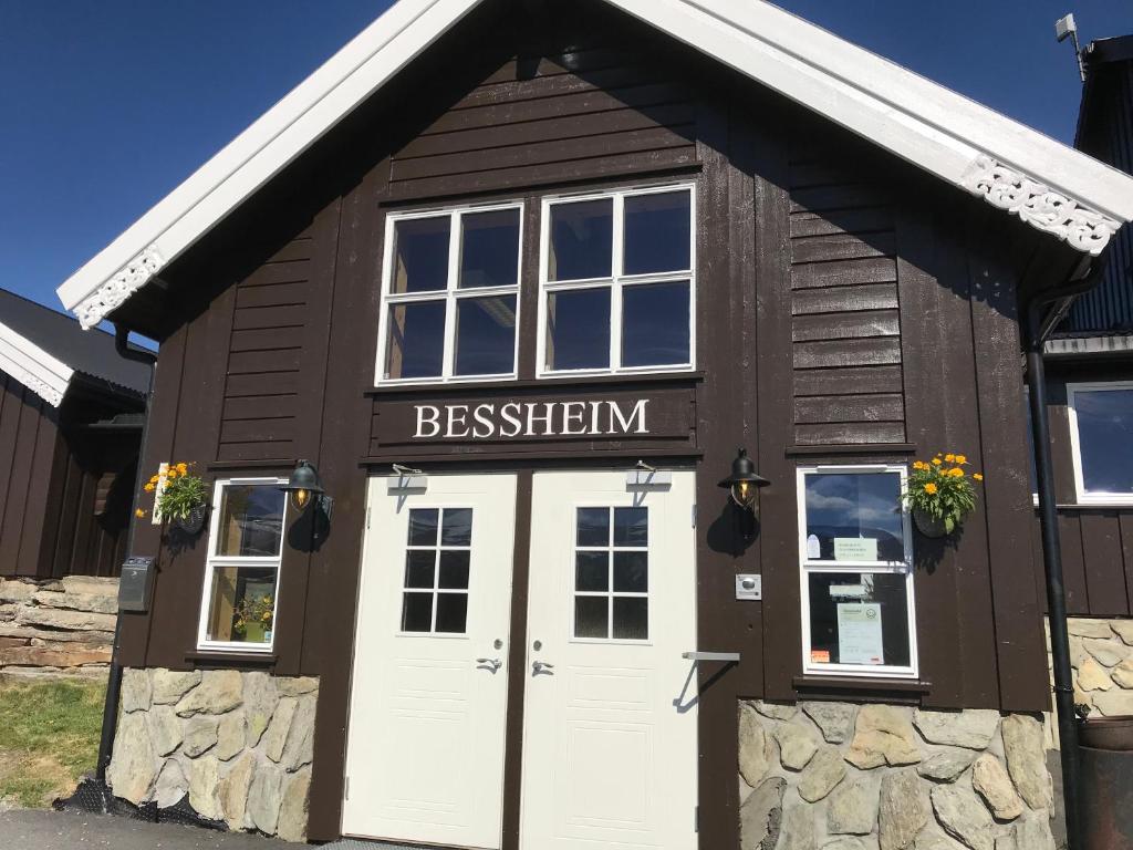 a brown building with white doors and a sign on it at Bessheim Fjellstue og Hytter in Bessheim