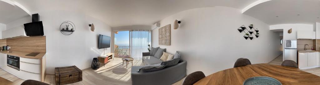 een woonkamer met een bank en een tafel bij "MER" Séjour détente tout confort, magnifique vue sur la mer in Canet-en-Roussillon