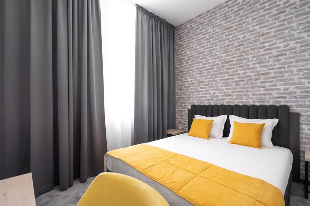 a bedroom with a bed with yellow pillows and a brick wall at ADEO HOTEL Sport & SPA in Ruse