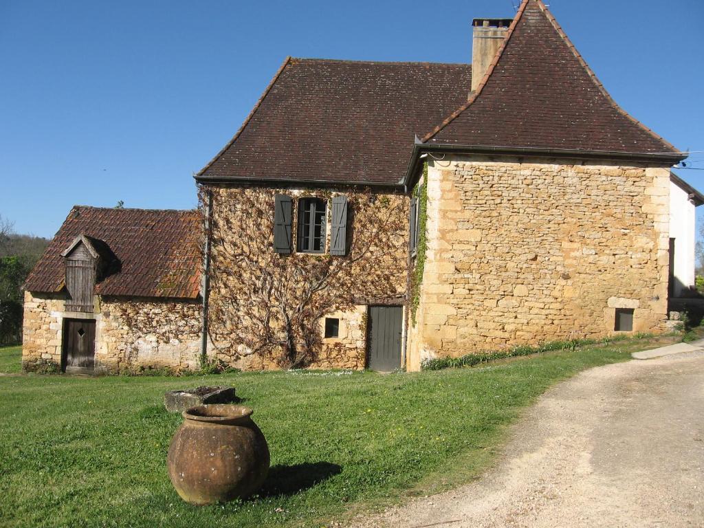 un viejo edificio de piedra con un jarrón delante de él en MAISON DE FAMILLE, en Cénac-et-Saint-Julien