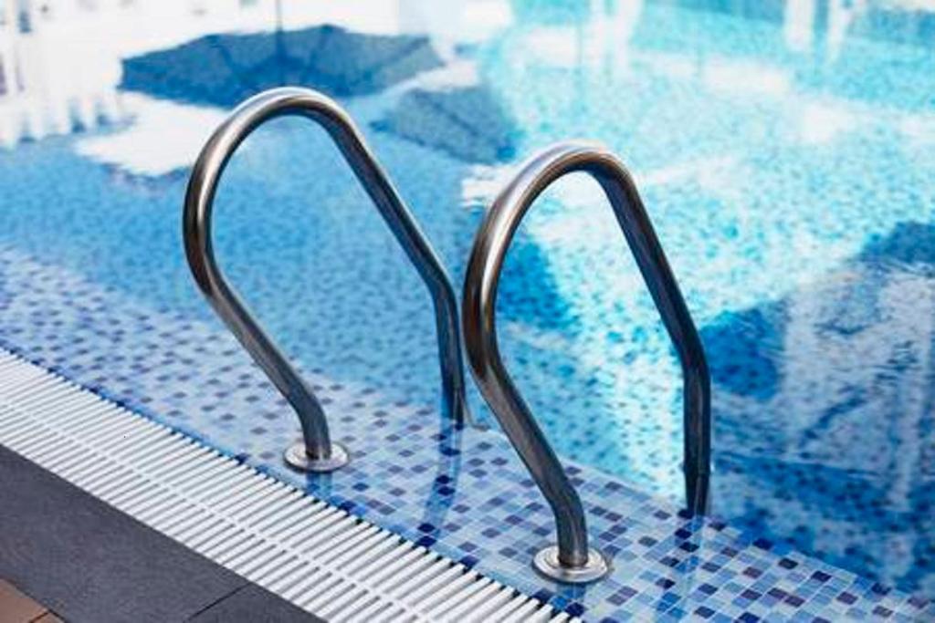 een zwembad met twee metalen rails in een zwembad bij Luxury private apartment at the beach in a 4 star hotel first beach line in Fuengirola