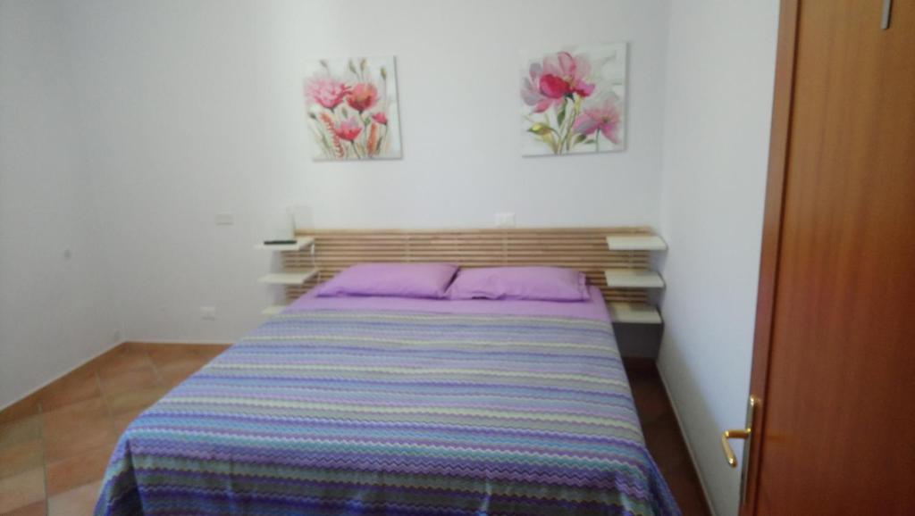 een bed in een kamer met twee schilderijen aan de muur bij Casetta Gaia in Latina