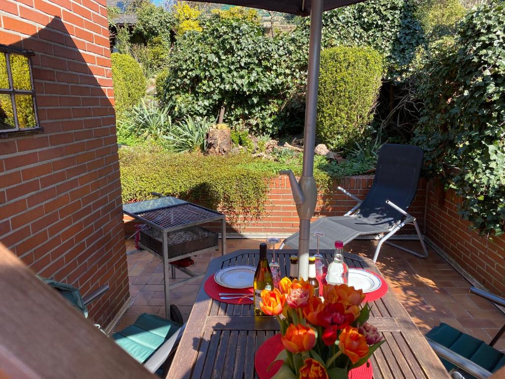 een patio met een tafel met bloemen erop bij Ferienwohnung "An der alten Mühle" 2 Schlafzimmer, Südbalkon, Gartenterrasse & Wallbox, 100 qm in Bad Bentheim