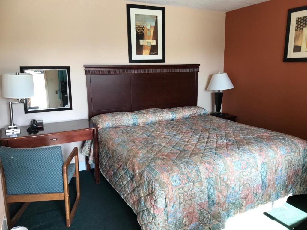 a hotel room with a bed and a desk and mirror at Travel Inn in Horseheads