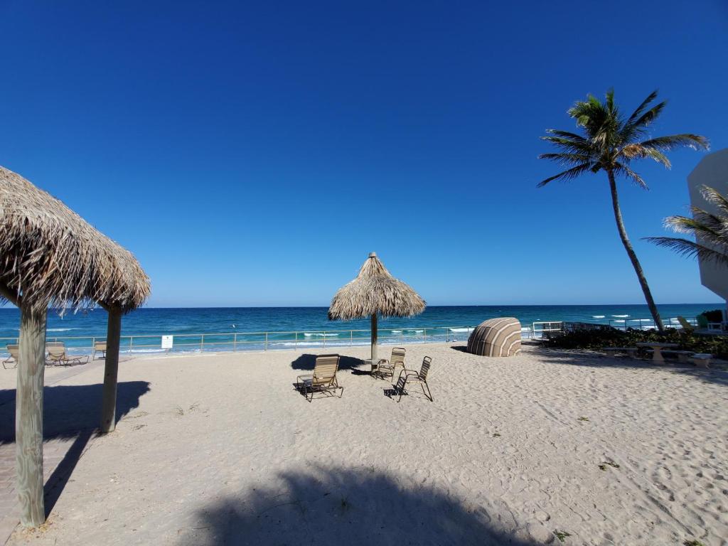 een strand met stoelen en parasols en de oceaan bij Ocean Side Resort - updated Villa in Hillsboro Beach