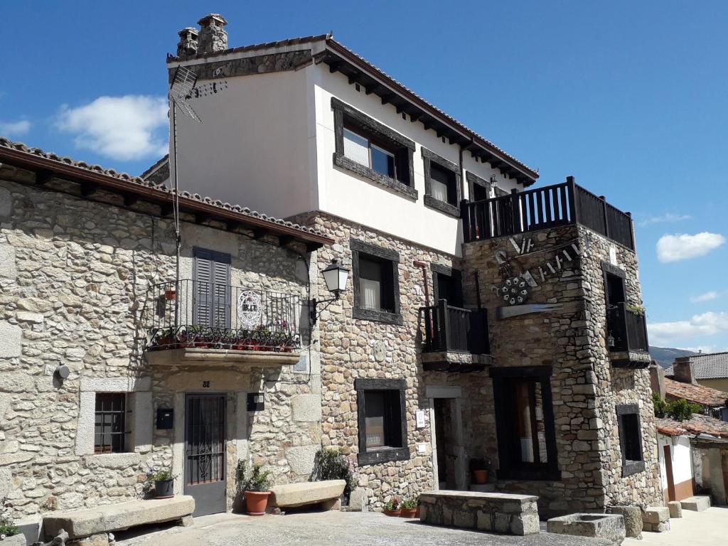 un edificio de piedra con un balcón en un lateral. en Vía Caparra Superior, en Oliva de Plasencia