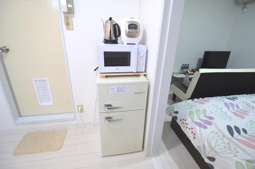宮崎市にあるComfort CUBE PHOENIX MIYAZAKIの小さな客室で、冷蔵庫の上に電子レンジが備わります。