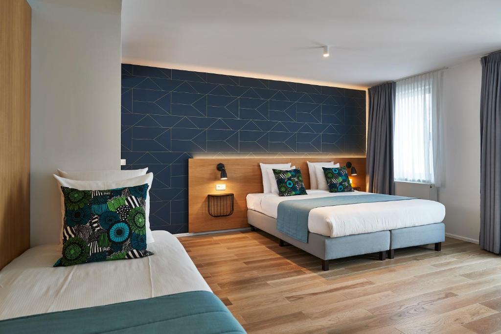 a bedroom with two beds and a blue accent wall at Hygge Hotel in Brussels