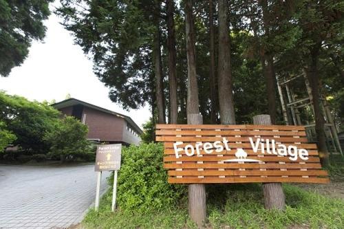 un banco de madera con las palabras "aldea del bosque". en Showa Forest Village, en Chiba