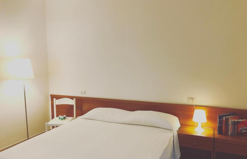 - une chambre avec un lit blanc et une lampe dans l'établissement Grazioso appartamento a due passi dal mare, à Cervia