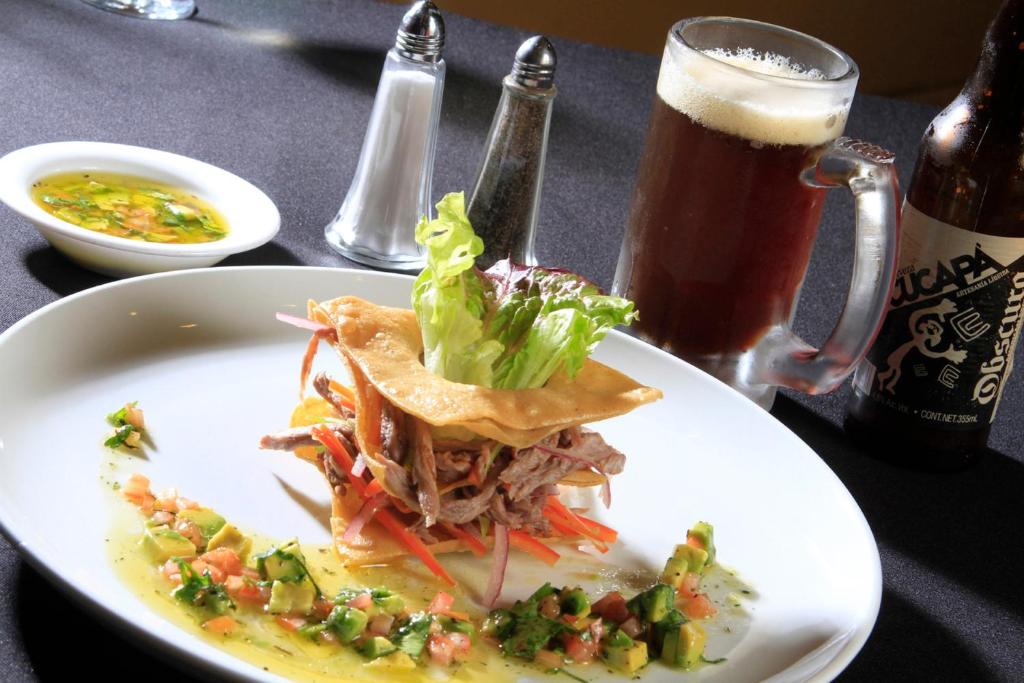 a plate of food on a table with a glass of beer at Holiday Inn Monterrey-Parque Fundidora by IHG in Monterrey