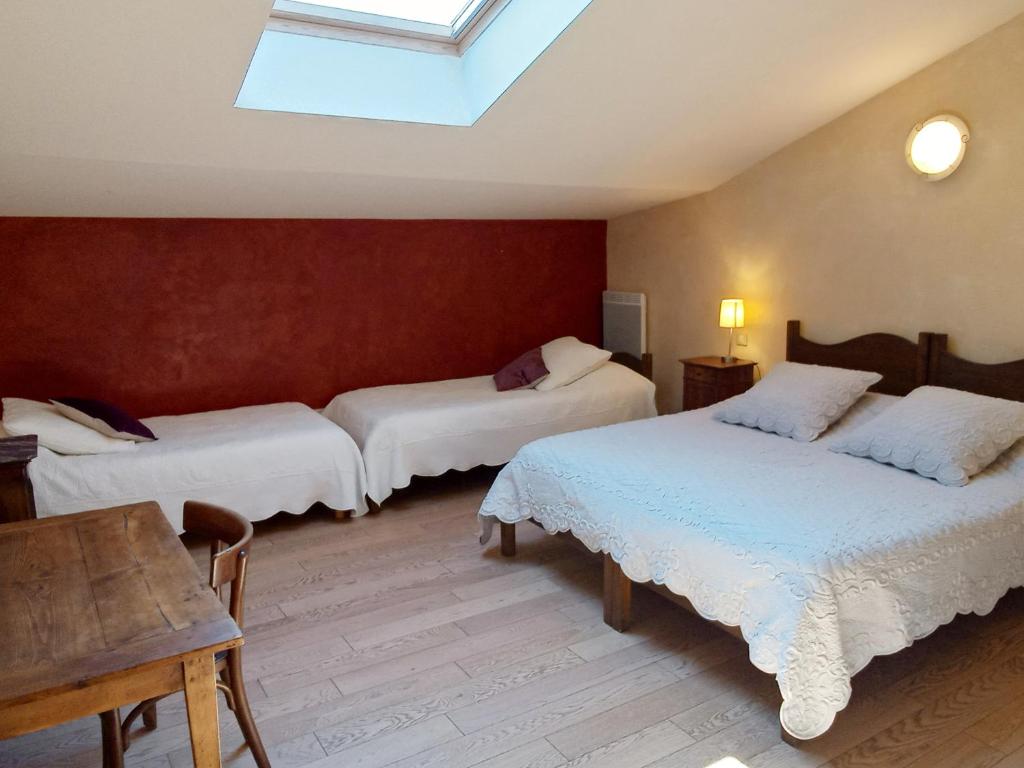 a bedroom with two beds and a skylight at Des Lits Sur La Place in Hérépian