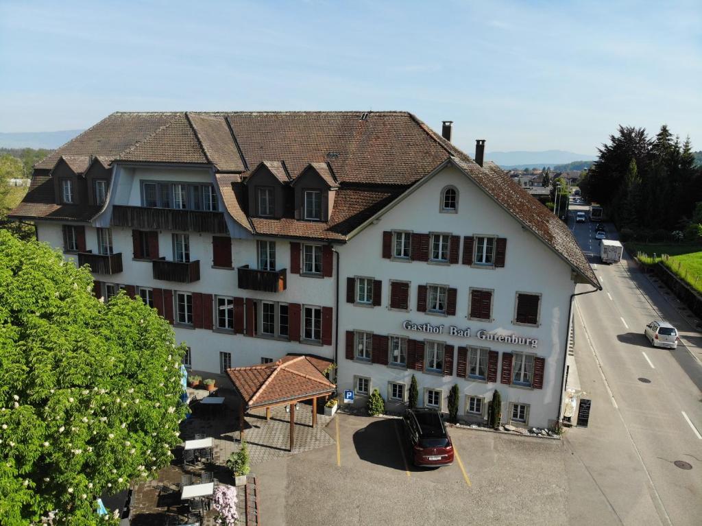 un gran edificio blanco con un coche aparcado delante de él en Hotel Restaurant Bad Gutenburg, en Lotzwil