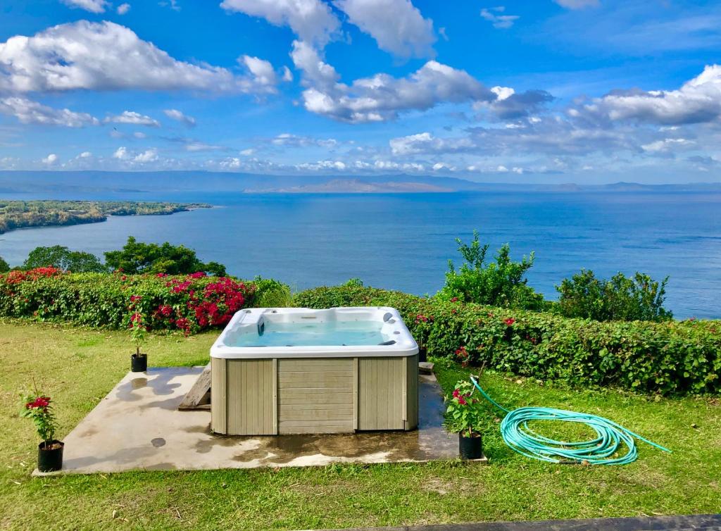 a hot tub in the grass with a view of the ocean at Ataalaya Farmhouse in Batangas City