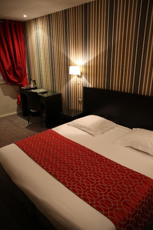 a hotel room with a bed with a red blanket at Grand Hôtel d&#39;Orléans in Toulouse