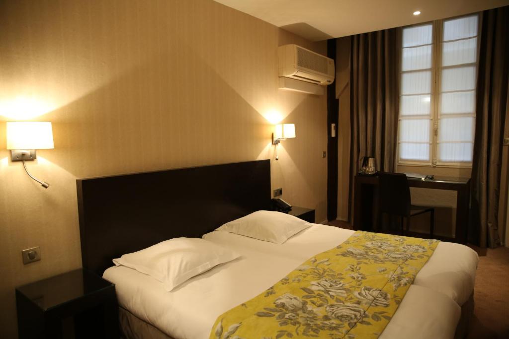 a hotel room with a large bed with a yellow blanket at Grand Hôtel d&#39;Orléans in Toulouse