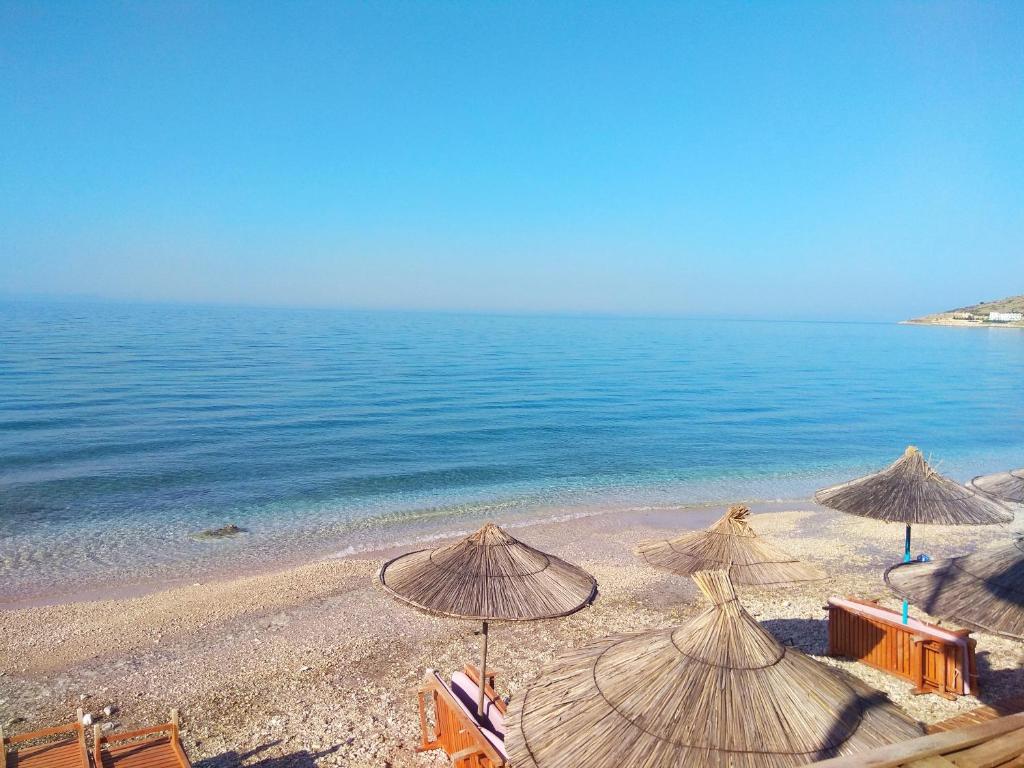 uma praia com guarda-sóis e cadeiras e o oceano em Qeparo Pano Rooms em Qeparo