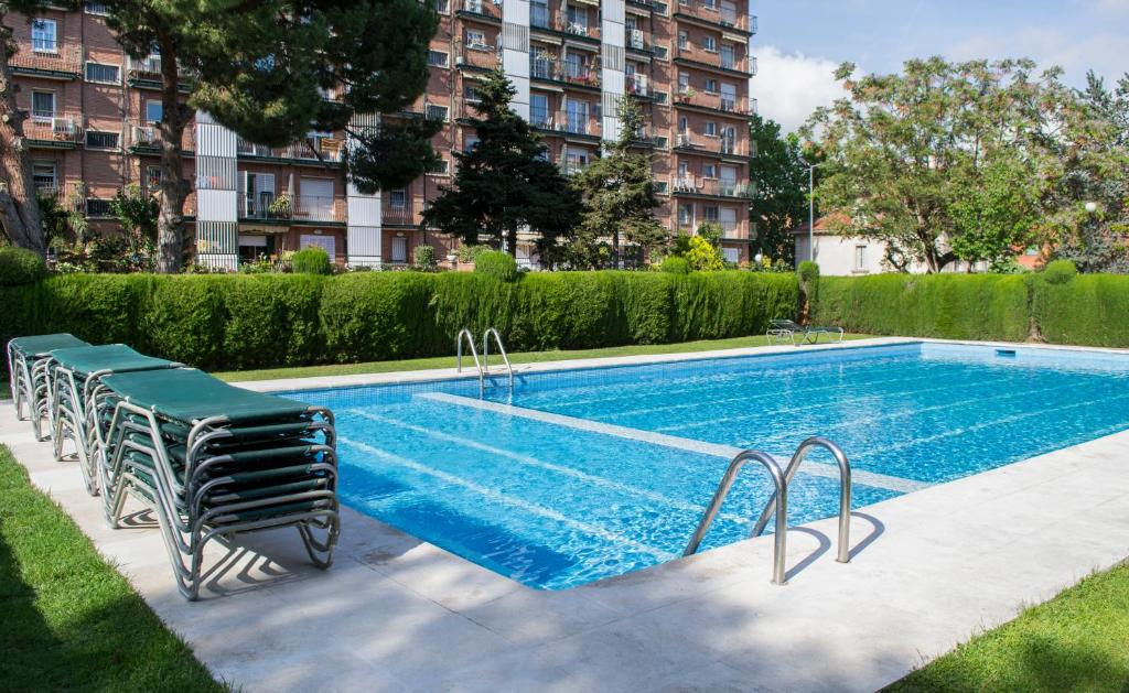 a swimming pool with chairs next to a building at Happy People Maragall in Barcelona