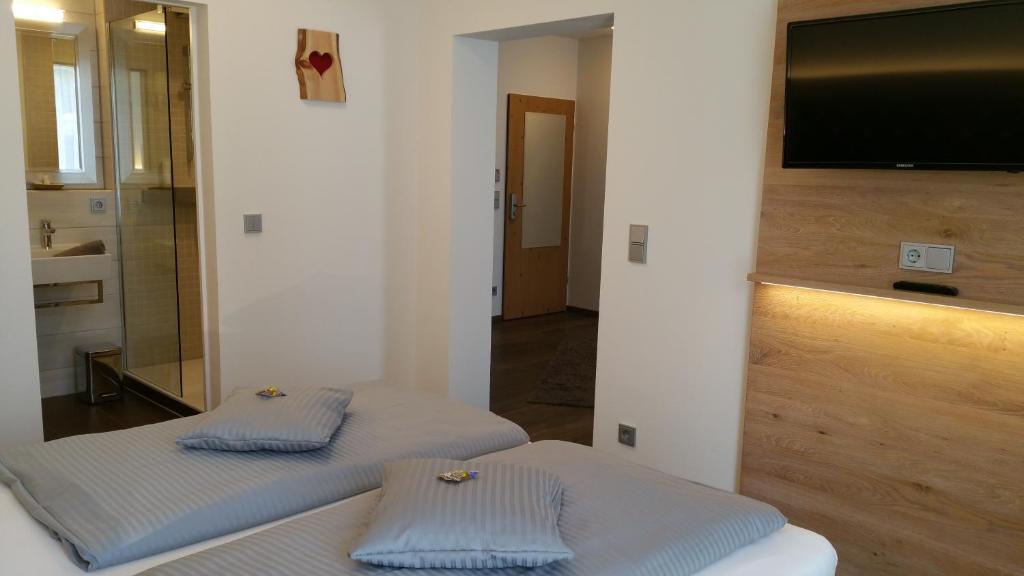 a room with two beds and a flat screen tv at Landhotel Böld Oberammergau in Oberammergau