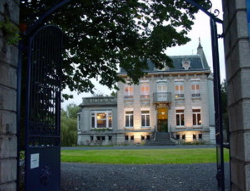 an open gate to a large building with lights on at Au Château Des Thermes in Saint-Amand-les-Eaux