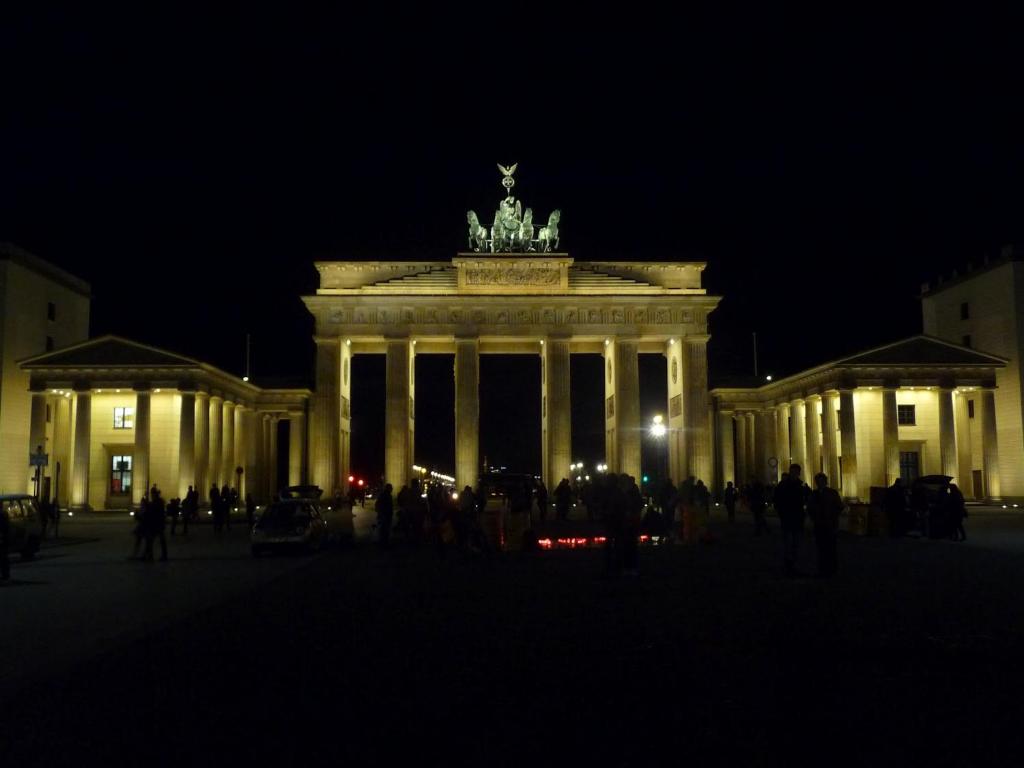 a large building with people standing in front of it at night at Apartment&Rooms near Brandenburg Gate in Berlin