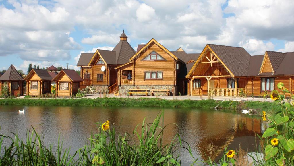 ein großes Holzhaus mit einem Teich davor in der Unterkunft Volna Hotel in Schytomyr