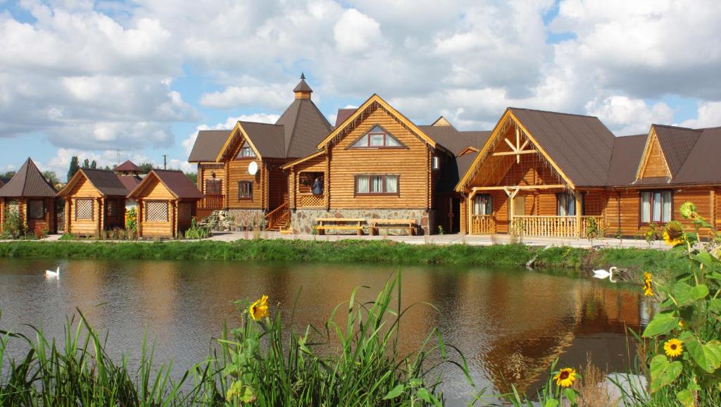 a large wooden house with a pond in front of it at Volna Hotel in Zhytomyr