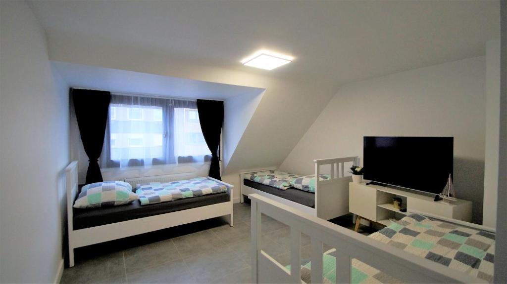 um pequeno quarto com 2 camas e uma televisão em Maye Oberhausen City Deluxe em Oberhausen