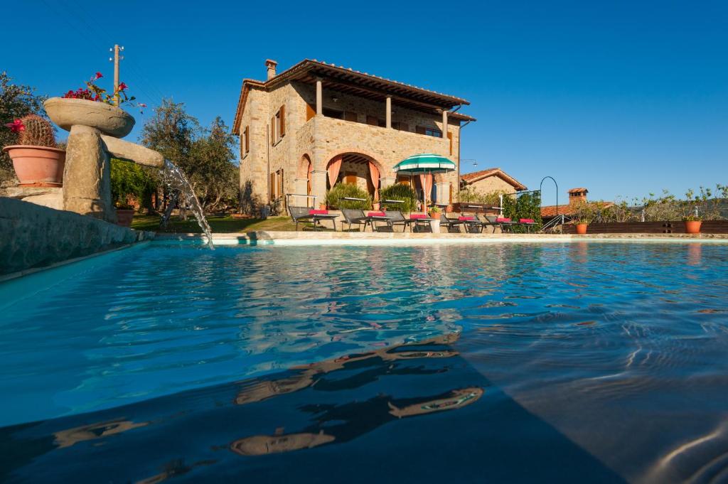 una piscina con una casa en el fondo en Villa Senaia, en Castiglion Fiorentino