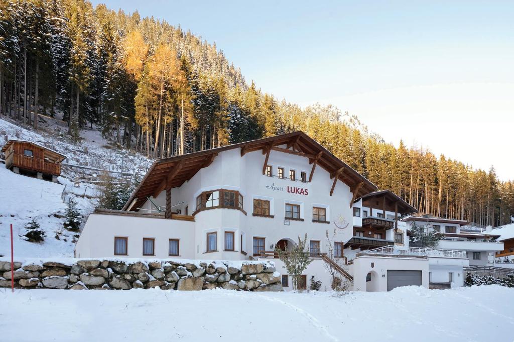 ein großes weißes Gebäude im Schnee mit Bäumen in der Unterkunft Apart Lukas in Ischgl