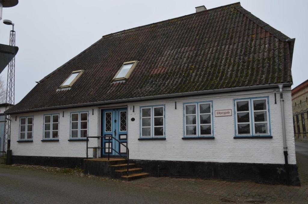 une maison blanche avec un toit marron et des portes bleues dans l'établissement Høkeriet C, à Nordborg