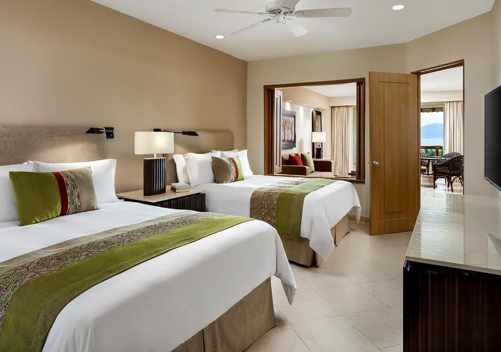 Cette chambre comprend deux lits et une télévision. dans l'établissement Grand Velas Riviera Nayarit, à Nuevo Vallarta
