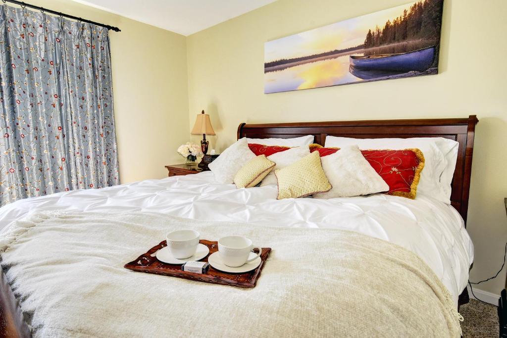 a bed with two cups and a tray on it at KY Cottage, with hot tub and lake view, on the Bourbon Trail in Taylorsville