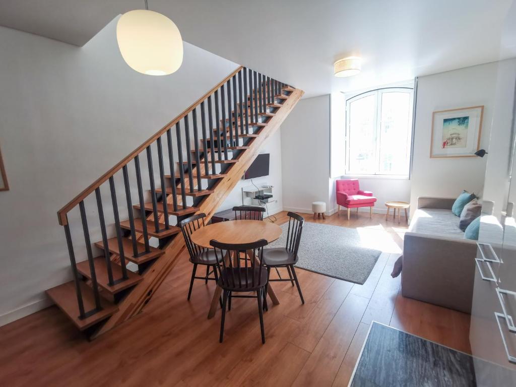 ein Wohnzimmer mit einer Treppe, einem Tisch und Stühlen in der Unterkunft Fanqueiros Apartment in Lissabon