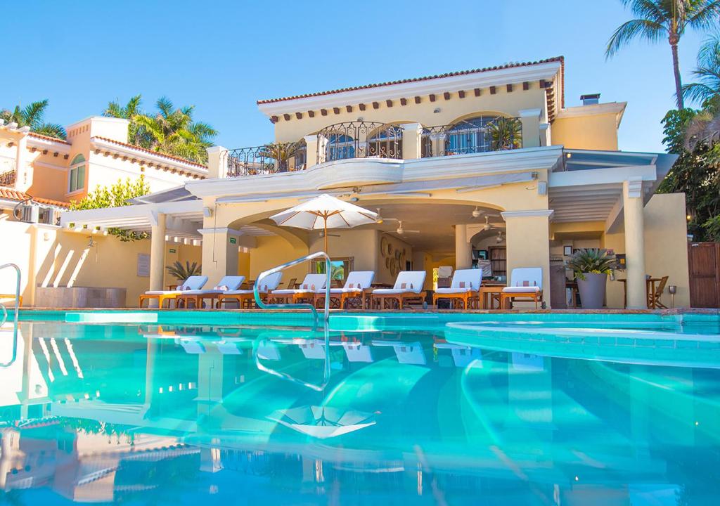 a villa with a swimming pool in front of a house at Casa Velas Adults Only All Inclusive in Puerto Vallarta