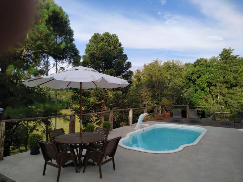 une terrasse avec une table, un parasol et une piscine dans l'établissement Recanto Berço das Aguas, à Piraquara