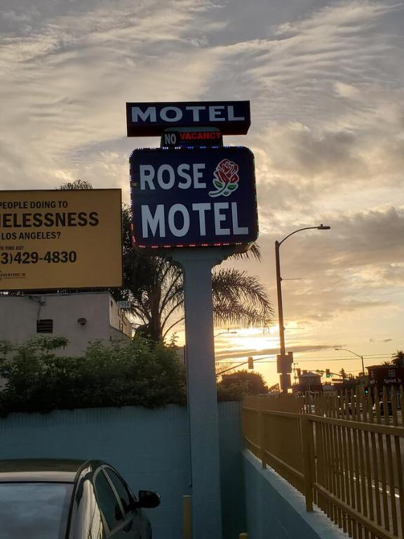 una señal de motel frente a una carretera con coche en Rose motel, en Compton