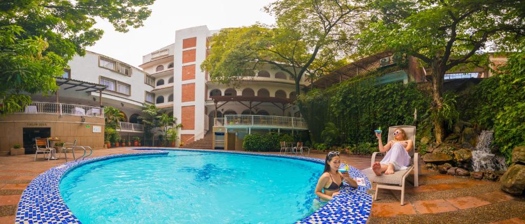 dos chicas sentadas en sillas junto a una piscina en Hotel Chicala en Neiva