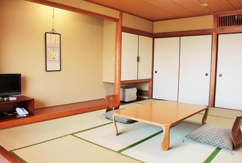 a living room with a table and a tv at Miyajima Seaside Hotel in Miyajima