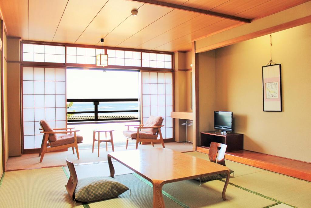 een woonkamer met een tafel en stoelen en een televisie bij Miyajima Seaside Hotel in Miyajima