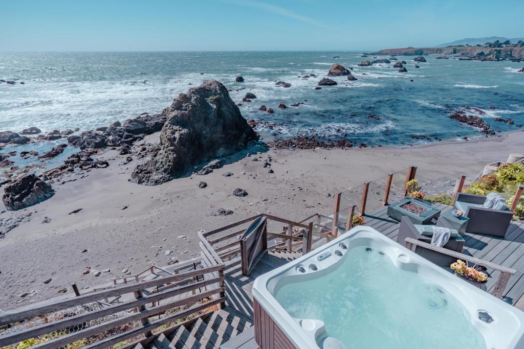 a hot tub on a beach next to the ocean at Surfscape Beach House, Private Beach & Ocean views in Bodega Bay