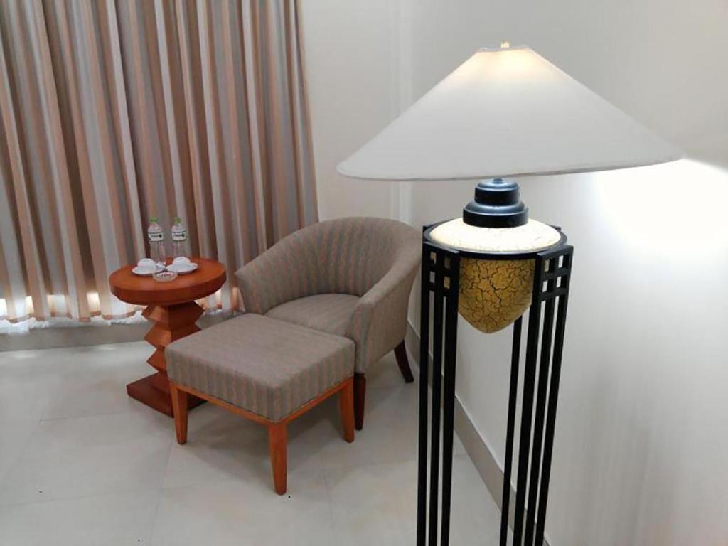 a room with a chair and a lamp and a table at Semec Hotel Nghi Son in Tĩnh Gia