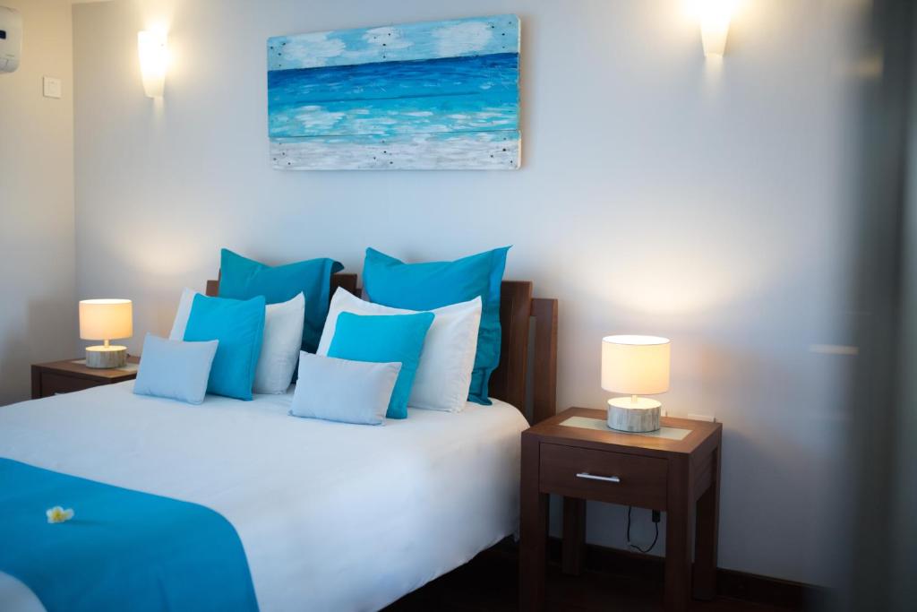 a bedroom with a bed with blue and white pillows at Sea view Belle Haven Penthouse in Mont Choisy