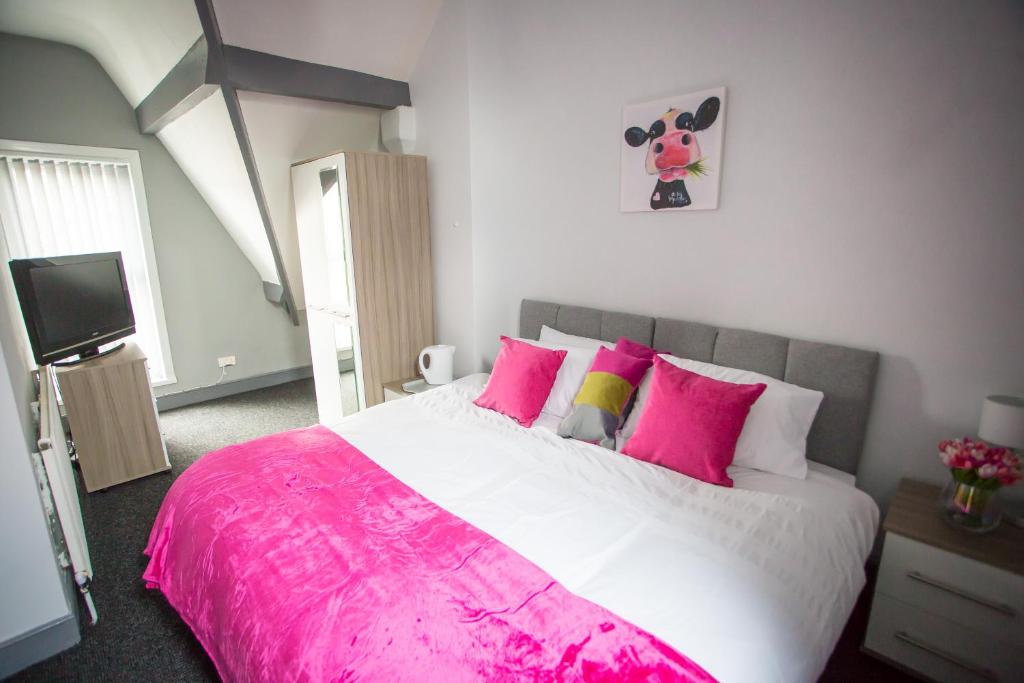 a bedroom with a large bed with pink pillows at Wray And Whyte House in Birmingham