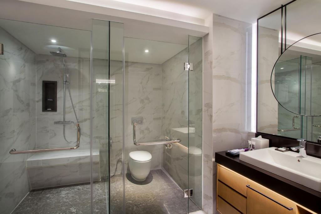 a bathroom with a shower and a toilet and a sink at Mercure Jakarta Batavia in Jakarta