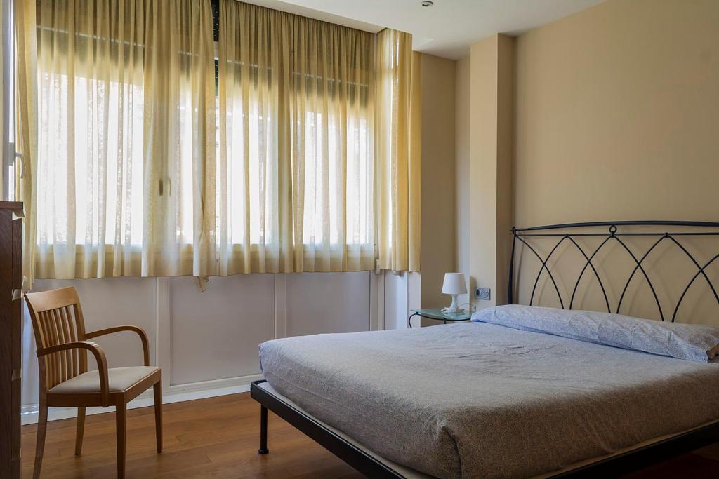 オンダリビアにあるPaseo Butrón by Basquelidaysのベッドルーム1室(ベッド1台、椅子、窓付)