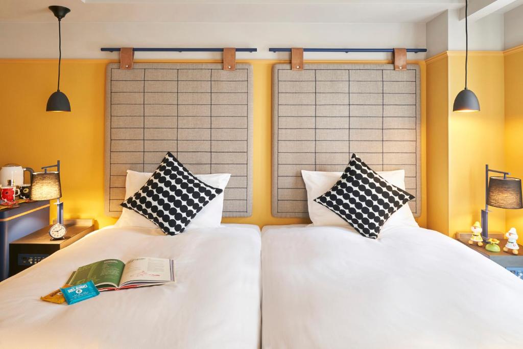 dwa łóżka z poduszkami i książką na nich w obiekcie Hotel Resol Yokohama Sakuragicho w mieście Jokohama