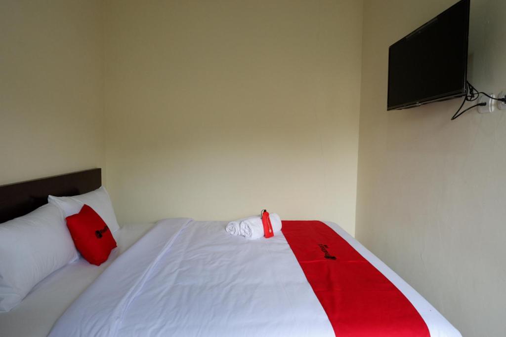 ein Bett mit einer roten und weißen Decke drauf in der Unterkunft RedDoorz near Terminal Mendolo Wonosobo in Wonosobo