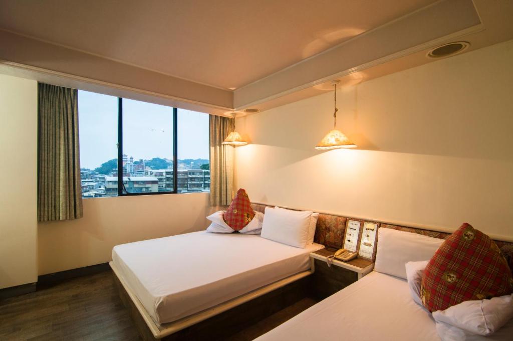 a hotel room with two beds and a window at Dahua Hotel in Keelung