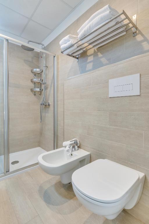 a bathroom with a toilet and a shower and a sink at Hotel Ambassador in Caorle
